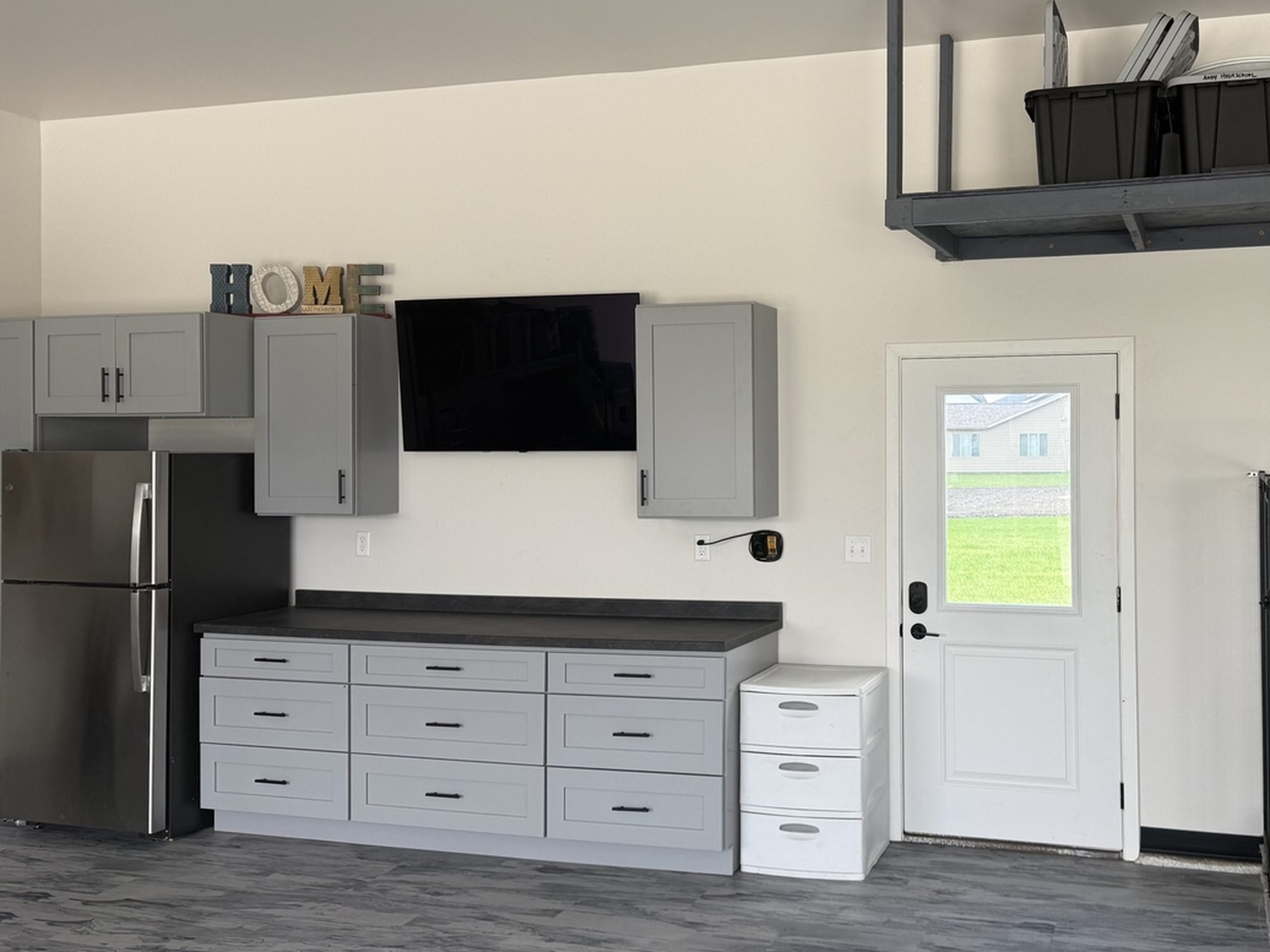After: finished 16-foot gray shaker garage cabinet run with dark laminate countertop over new gray wood-look LVT flooring in Mapleton, ND