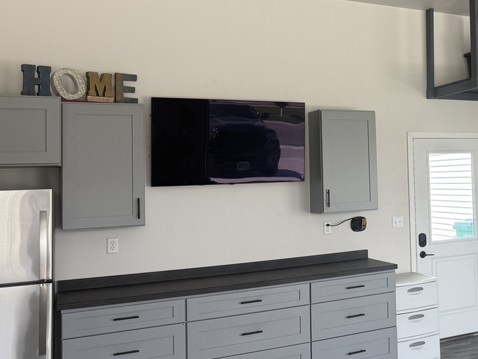 After: gray shaker garage cabinets and wall uppers running wall to wall over new gray wood-look LVT flooring