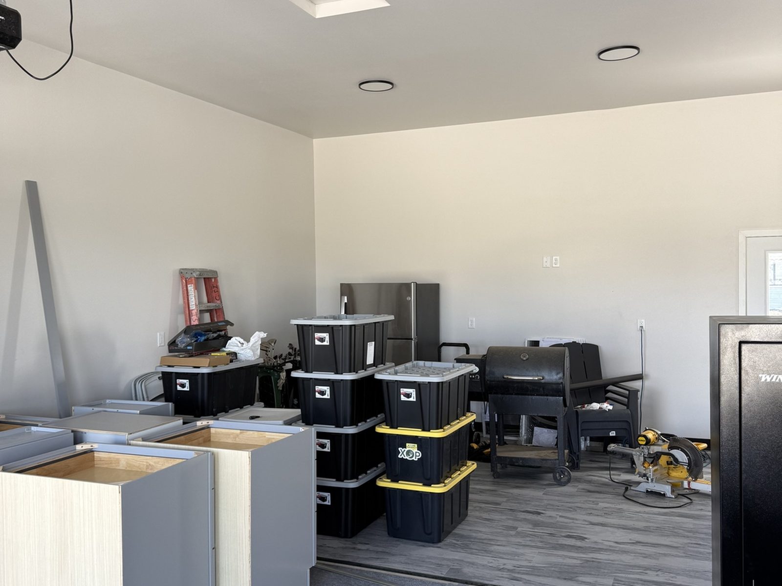 In progress: new gray wood-look LVT flooring down in a Mapleton, ND garage with cabinet boxes staged before assembly