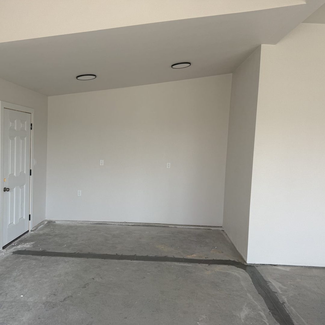 Before photo of the same Mapleton ND garage with bare concrete and an empty back wall