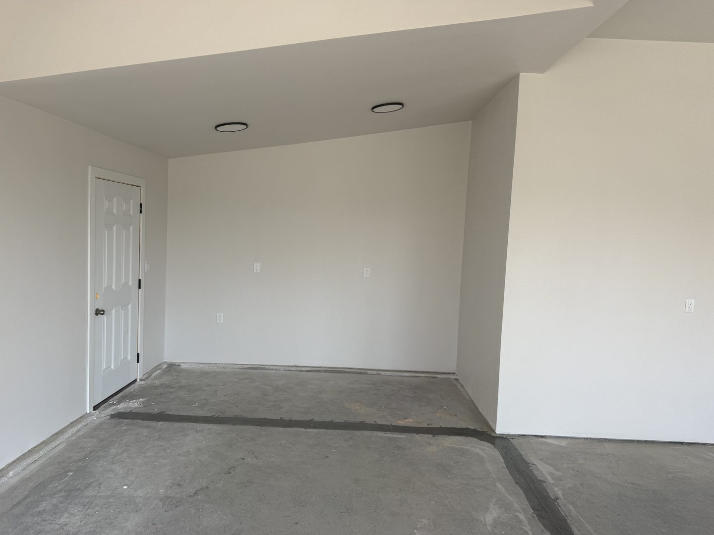 Before: the same Mapleton, ND garage with bare concrete, filled control joints, blank drywall and no storage on the back wall