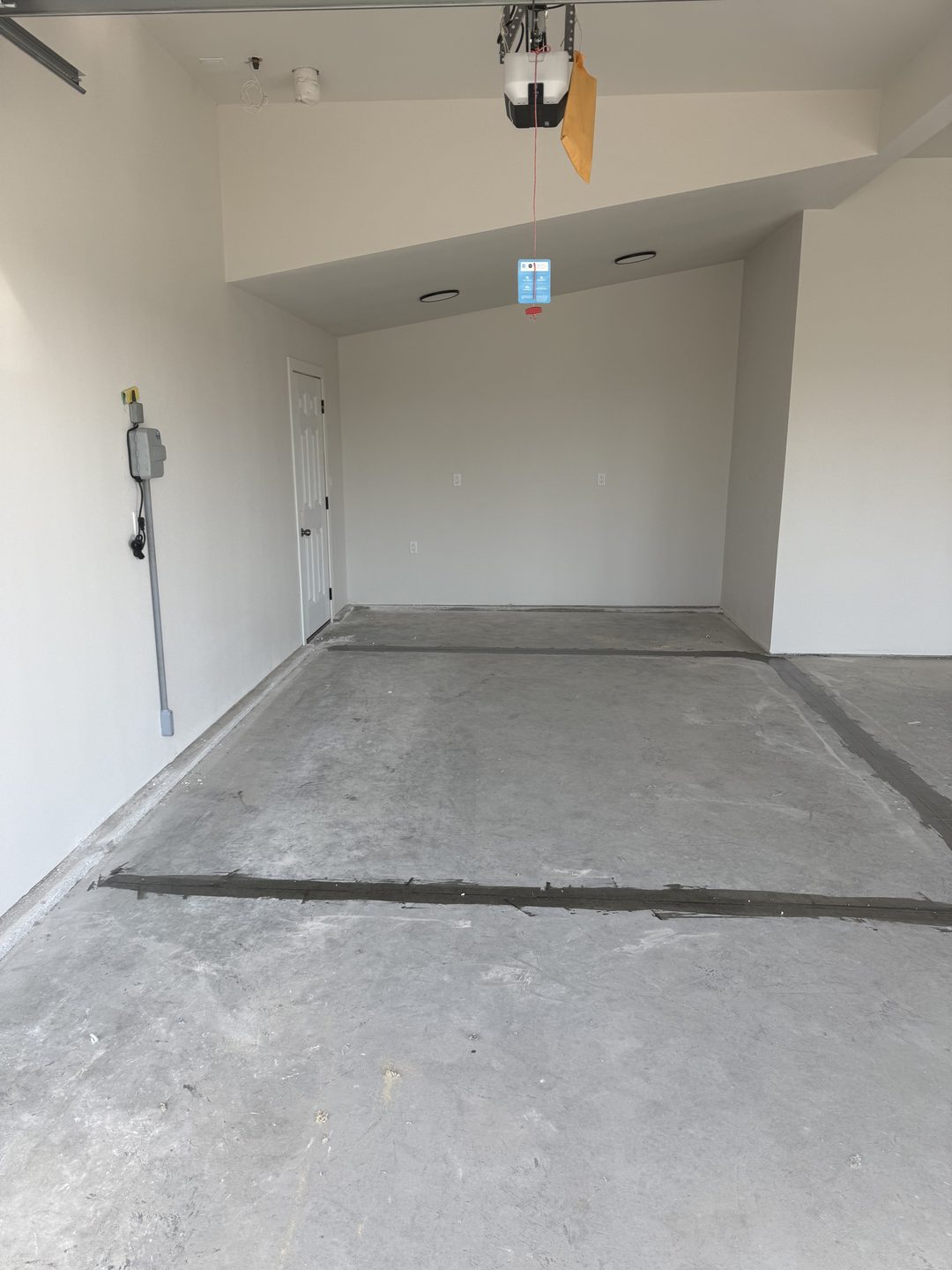 Before photo of a Mapleton ND garage from the overhead door with bare concrete, filled control joints and blank white walls