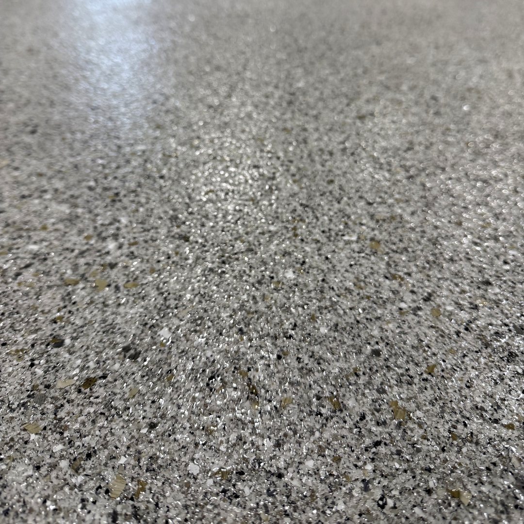 Close photo of a gray, white and black full-broadcast flake epoxy garage floor in Reiles Acres ND