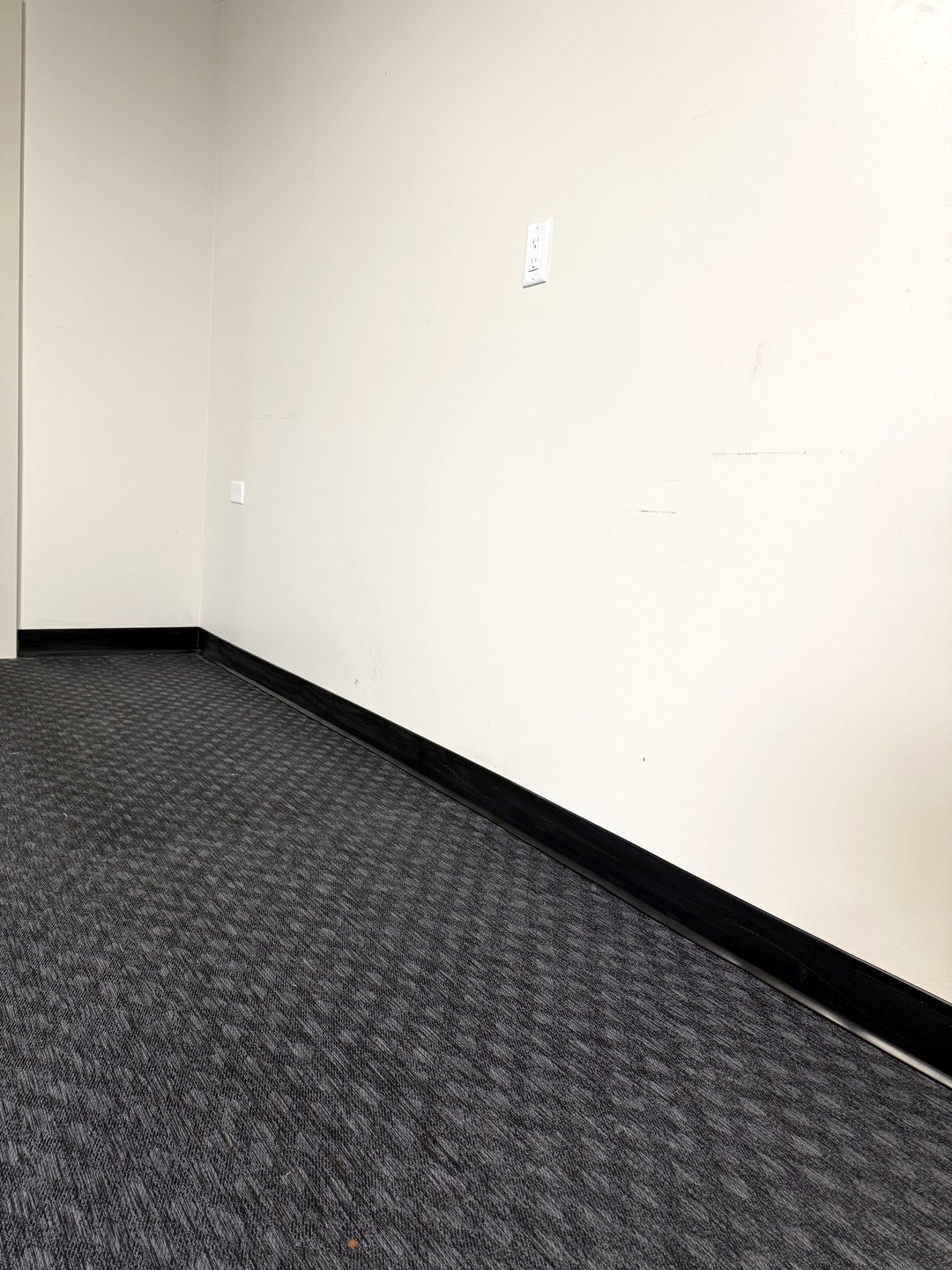 Photo of black vinyl base running along a white wall over rubber gym flooring in a Reiles Acres ND garage
